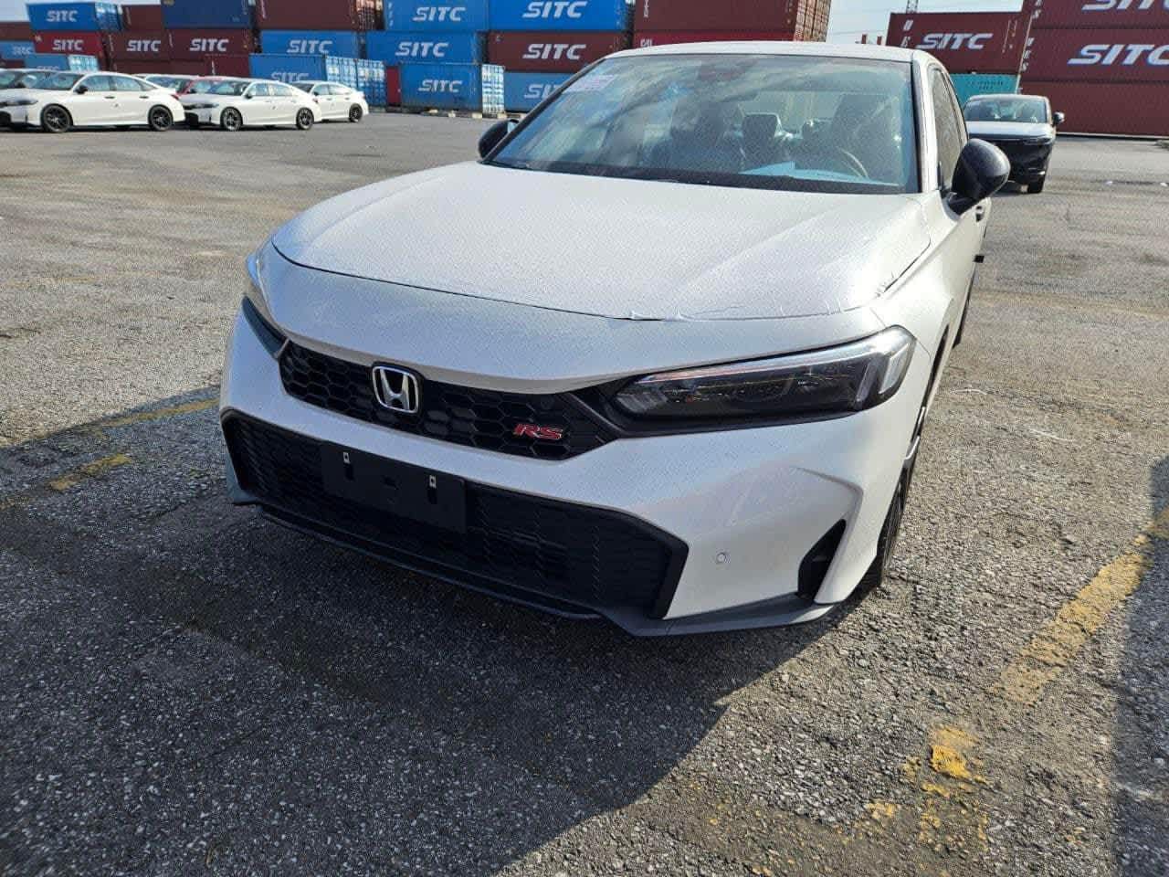 Giá xe Honda Civic cũ cập nhật 8 A new white Honda Civic RS sedan, likely a 2024 model, at a Vietnamese port.